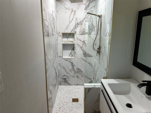 bathroom featuring tiled shower and vanity