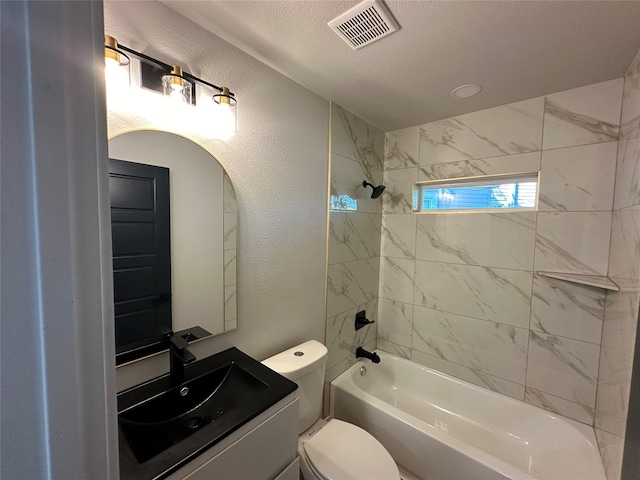 full bathroom featuring vanity, toilet, tiled shower / bath combo, and a textured ceiling