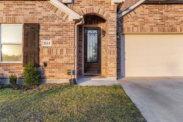 entrance to property with a garage and a lawn