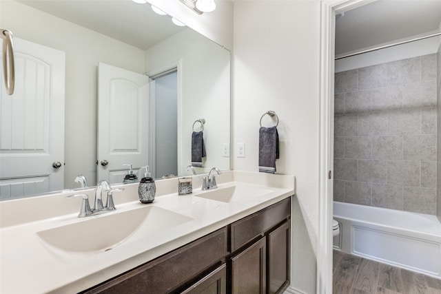 full bathroom with vanity, hardwood / wood-style floors, tiled shower / bath combo, and toilet