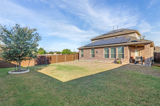 back of house with a patio, solar panels, and a lawn