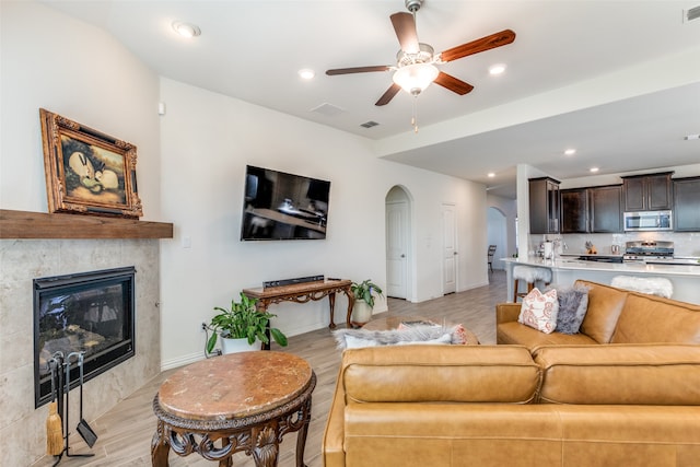 living room featuring a fireplace, light hardwood / wood-style floors, and ceiling fan