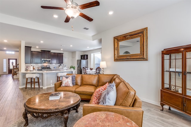 living room featuring plenty of natural light, sink, light wood-type flooring, and ceiling fan