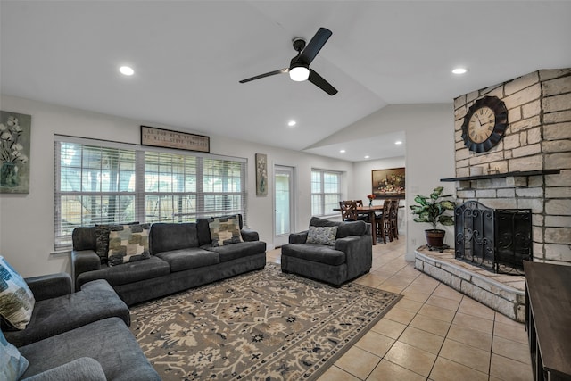 tiled living room featuring a stone fireplace, ceiling fan, and vaulted ceiling