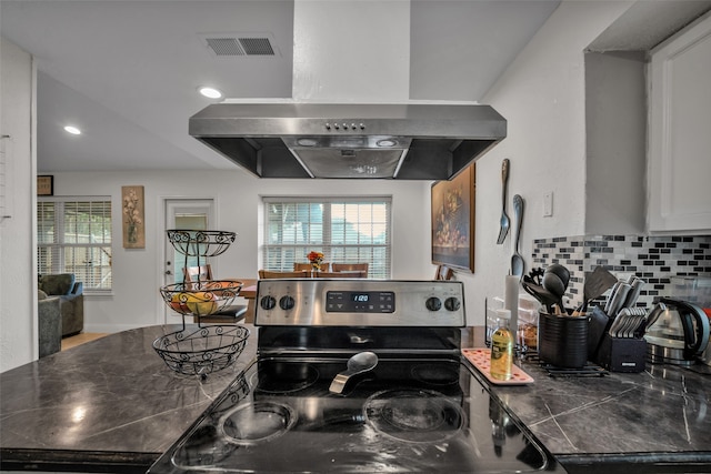 kitchen with island exhaust hood, stainless steel range with electric stovetop, decorative backsplash, and white cabinets