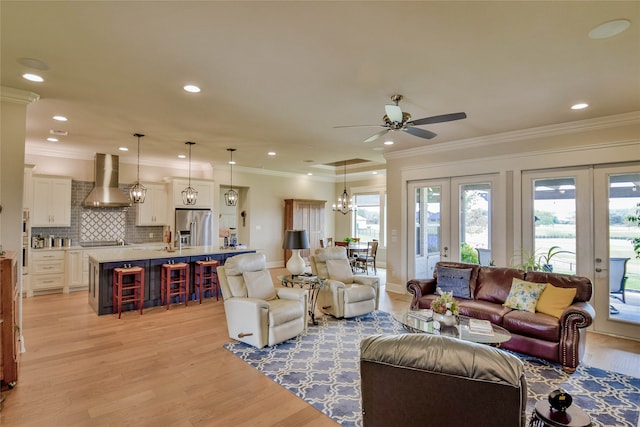 living room featuring ceiling fan, ornamental molding, and light wood-type flooring