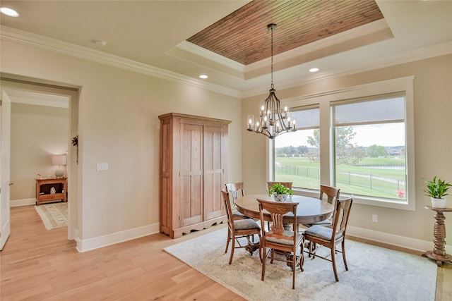 dining area with a wealth of natural light, ornamental molding, light hardwood / wood-style floors, and a raised ceiling