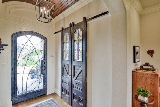 foyer entrance featuring a notable chandelier, a barn door, wood ceiling, and light wood-type flooring