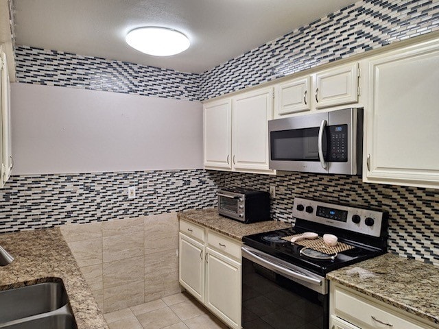 kitchen with tile walls, sink, light stone counters, and stainless steel appliances