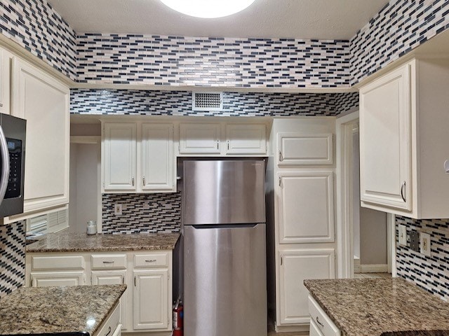 kitchen featuring backsplash, white cabinets, light stone counters, and stainless steel appliances