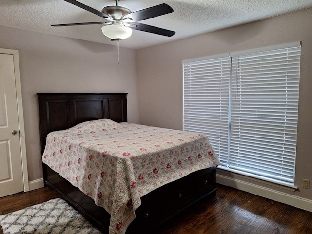 bedroom with a textured ceiling, ceiling fan, and dark hardwood / wood-style floors