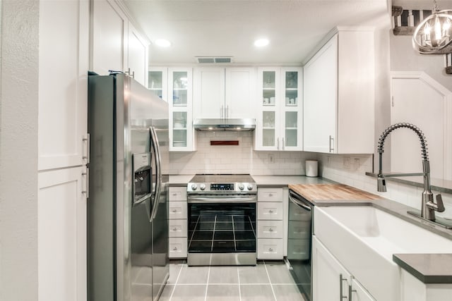 kitchen featuring tasteful backsplash, light tile patterned floors, white cabinetry, sink, and stainless steel appliances