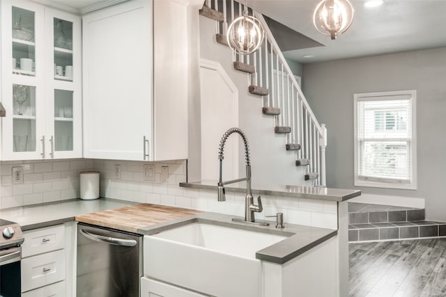 kitchen with white cabinetry, dishwasher, dark wood-type flooring, decorative light fixtures, and sink