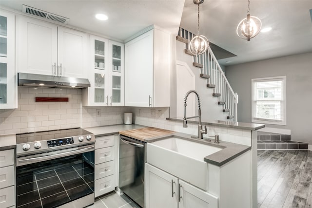 kitchen with kitchen peninsula, sink, light wood-type flooring, white cabinetry, and appliances with stainless steel finishes