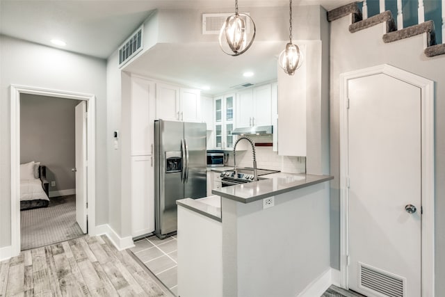 kitchen with kitchen peninsula, light hardwood / wood-style floors, stainless steel appliances, decorative light fixtures, and white cabinets