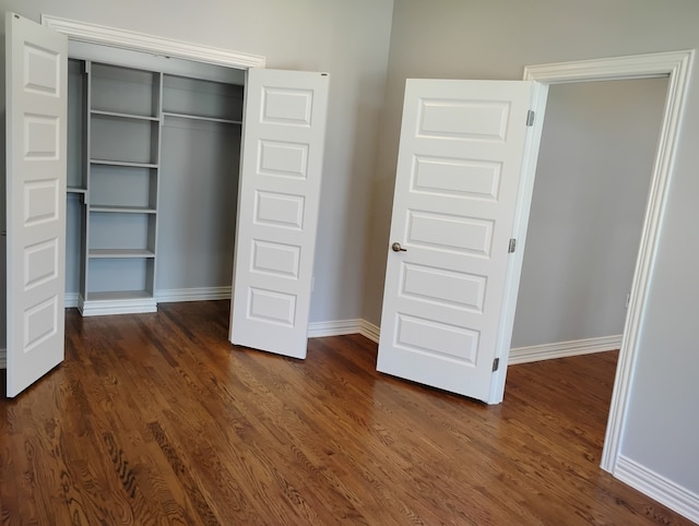 unfurnished bedroom with dark hardwood / wood-style floors and a closet