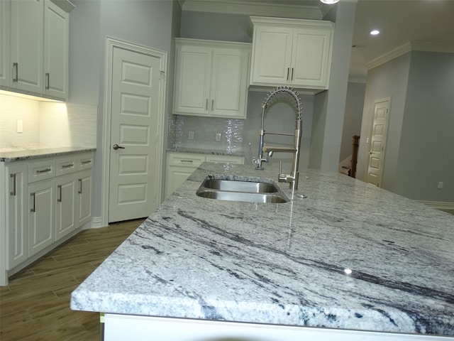 kitchen featuring tasteful backsplash, white cabinetry, ornamental molding, and sink