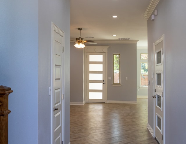 foyer entrance with wood-type flooring, ceiling fan, and crown molding