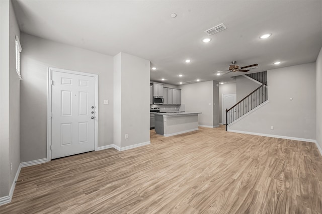 unfurnished living room with light wood-type flooring and ceiling fan