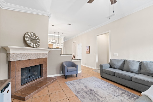 living room featuring crown molding, light tile patterned floors, a fireplace, and ceiling fan