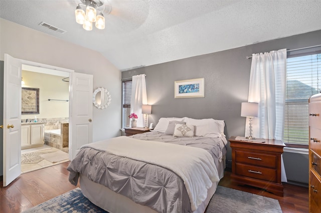 bedroom with wood-type flooring, ensuite bath, a textured ceiling, ceiling fan, and vaulted ceiling