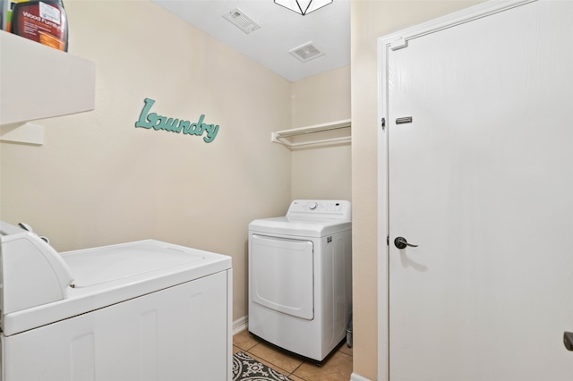 clothes washing area with light tile patterned floors and washing machine and clothes dryer