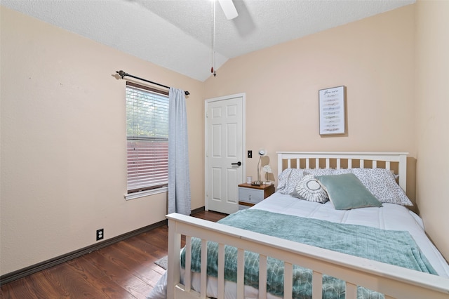 bedroom with ceiling fan, a textured ceiling, vaulted ceiling, and dark hardwood / wood-style flooring