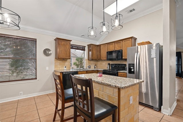 kitchen with light stone countertops, black appliances, hanging light fixtures, and a kitchen island