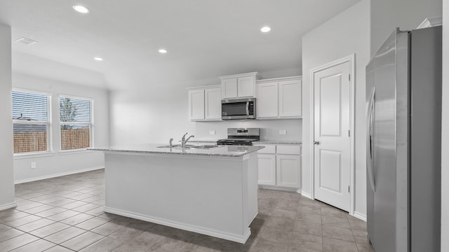 kitchen featuring light stone countertops, a kitchen island with sink, stainless steel appliances, and white cabinets