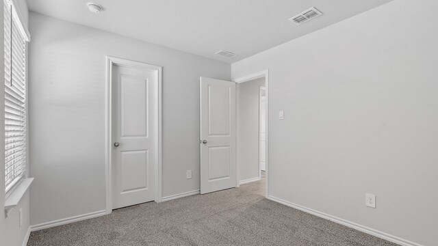 unfurnished bedroom featuring light carpet and multiple windows