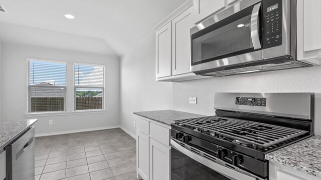 kitchen with white cabinets, stainless steel appliances, light stone counters, and light tile patterned floors