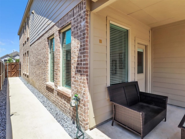 view of side of property featuring brick siding, fence, and a gate