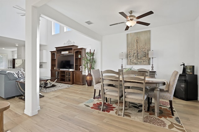 dining area featuring a towering ceiling, light wood-type flooring, and ceiling fan