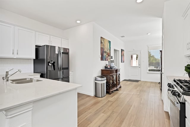 kitchen featuring stainless steel appliances, light hardwood / wood-style floors, sink, light stone counters, and white cabinets