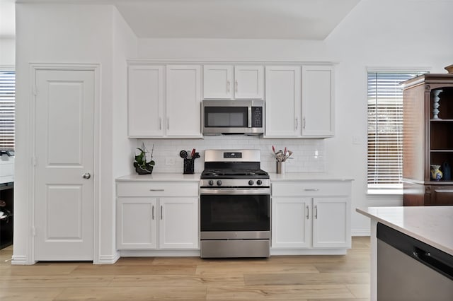 kitchen with light hardwood / wood-style flooring, backsplash, appliances with stainless steel finishes, and white cabinets