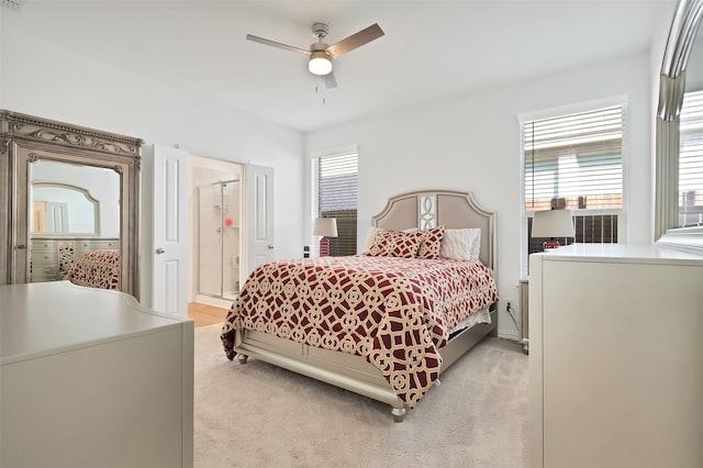 bedroom with ceiling fan, connected bathroom, and light carpet