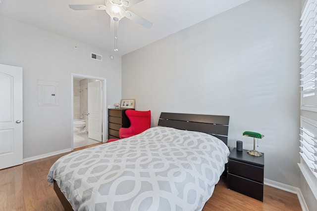 bedroom featuring light hardwood / wood-style flooring, ensuite bath, electric panel, and ceiling fan