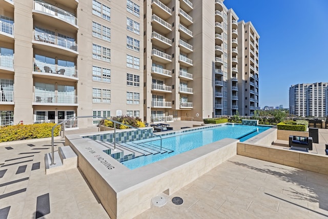 view of pool with a hot tub and a patio