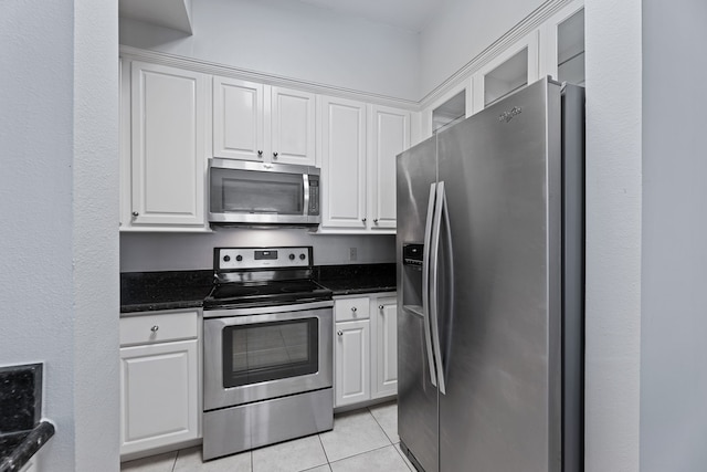 kitchen featuring white cabinetry, stainless steel appliances, and dark stone counters