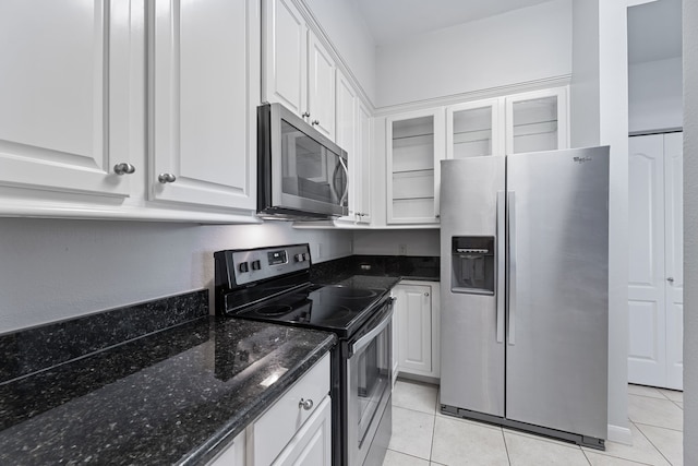 kitchen featuring white cabinets, dark stone countertops, stainless steel appliances, and light tile patterned floors