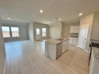 kitchen with white cabinetry, light hardwood / wood-style flooring, an island with sink, and dishwasher