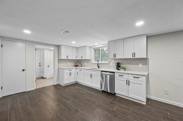 kitchen featuring decorative backsplash, white cabinets, dark hardwood / wood-style flooring, stainless steel dishwasher, and sink