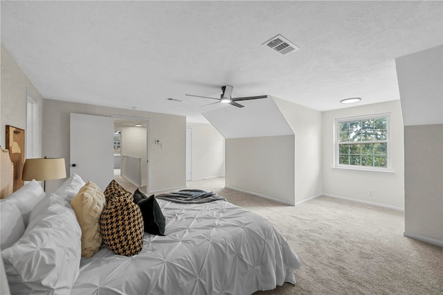 bedroom featuring lofted ceiling, a textured ceiling, light colored carpet, and ceiling fan