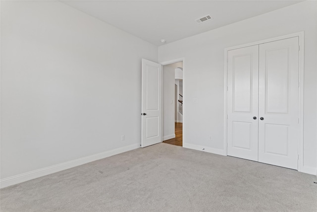 unfurnished bedroom with light carpet and a closet