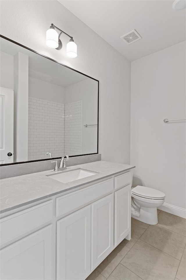 bathroom with tile patterned floors, vanity, tiled shower, and toilet