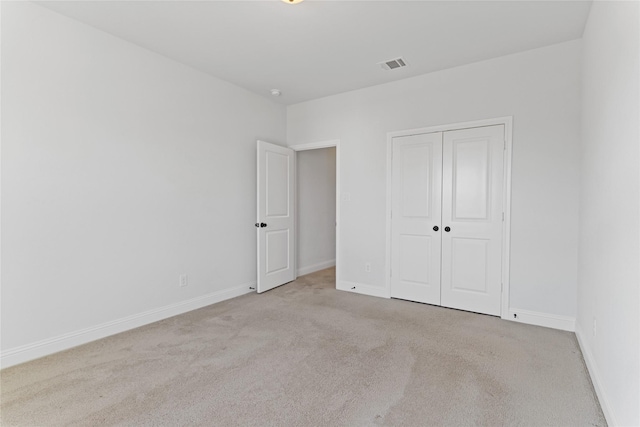 unfurnished bedroom featuring light colored carpet and a closet