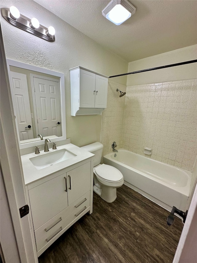 full bathroom featuring hardwood / wood-style flooring, toilet, tiled shower / bath, vanity, and a textured ceiling