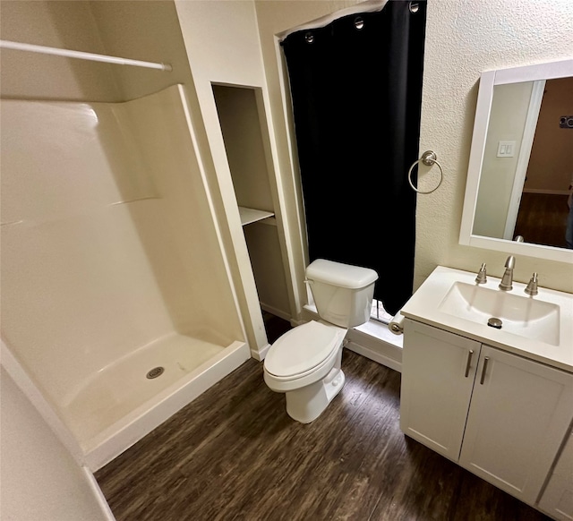 bathroom featuring toilet, walk in shower, hardwood / wood-style flooring, and vanity