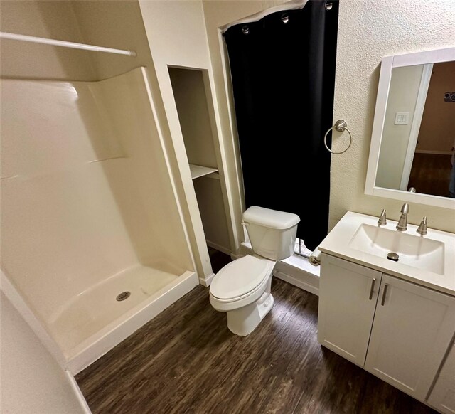 806 Mckinney Ave, Princeton, TX 75407 - full bathroom featuring vanity, toilet, baseboards, a shower stall, and wood finished floors