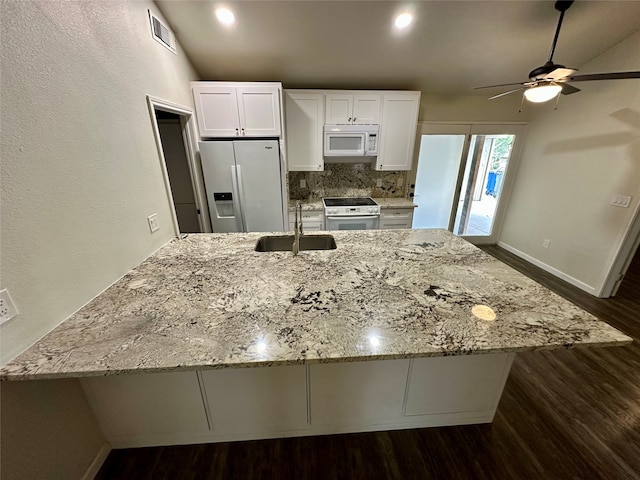 kitchen featuring tasteful backsplash, light stone counters, white cabinetry, sink, and white appliances